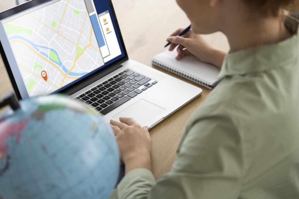 Person using a laptop to view a map with a location pin, notebook and pen nearby, illustrating local SEO strategies and digital marketing analysis.