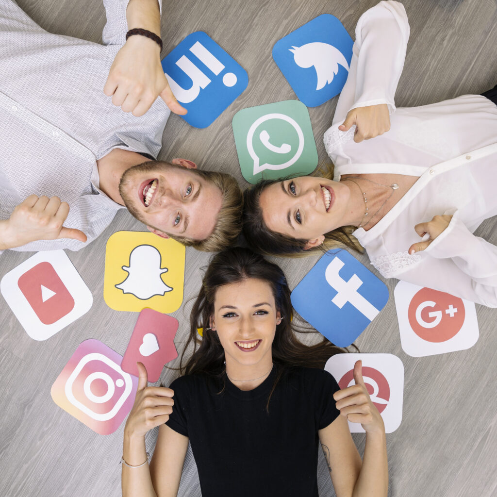 Young adults smiling and giving thumbs up, surrounded by social media logos including Facebook, Instagram, Twitter, and YouTube, representing social media engagement and brand visibility.
